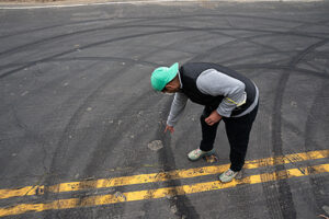 Reporter Jose Fermoso points at skid marks from tires left after a sideshow.