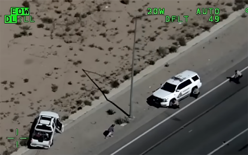 still from police helicopter camera that shows deputies aiming guns at car on side of road.