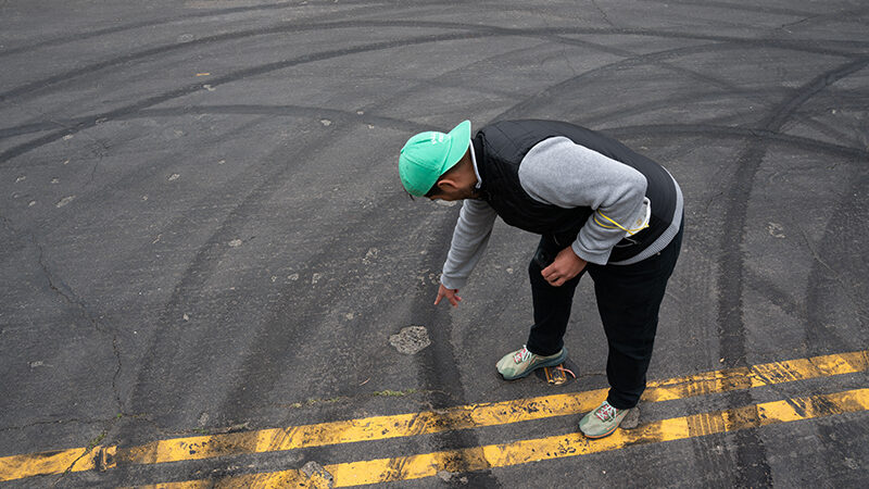 Reporter Jose Fermoso points at skid marks left at an intersection following a sideshow.